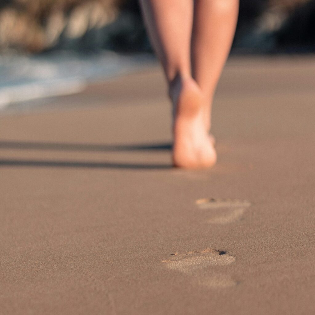 Close up shot of footprints in the sand with the person in the background